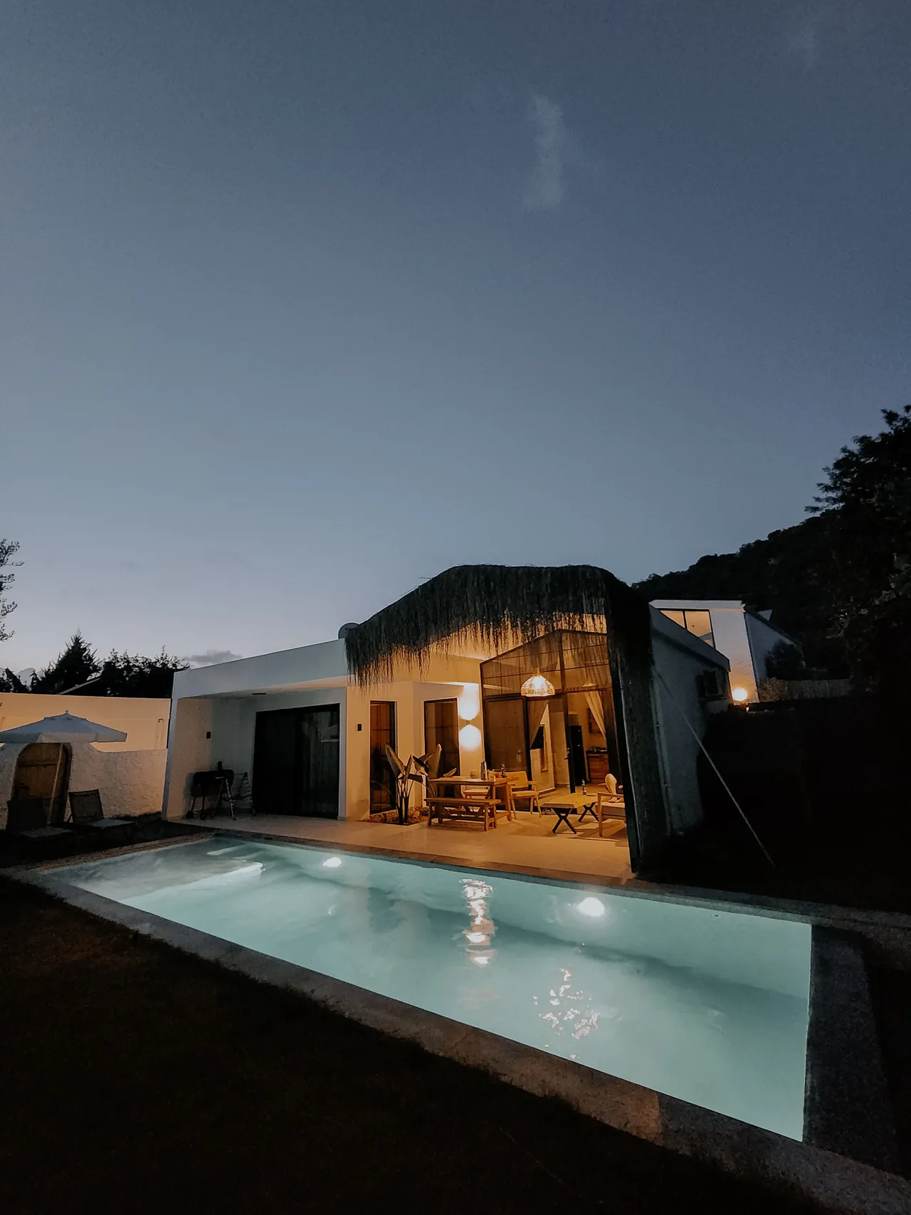 Casa con alberca al anochecer en una zona residencial