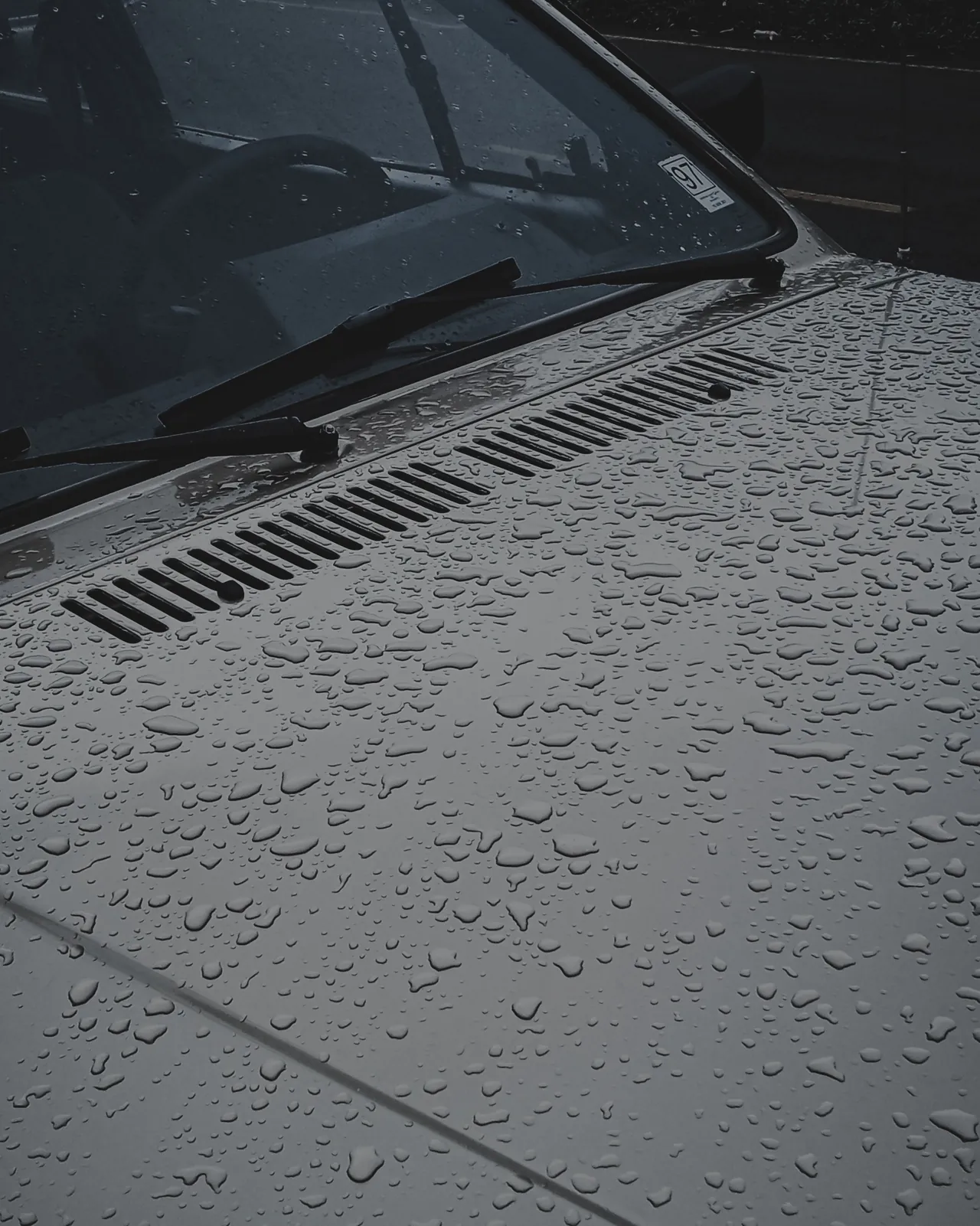 Gotas de agua sobre el cofre gris de un auto recién detallado